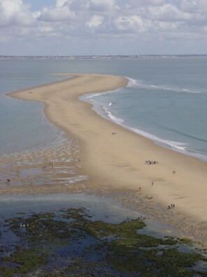 A beach with a wide sandy area and a clear view of the ocean.