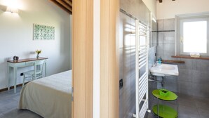 Ein Schlafzimmer mit Bett, Schreibtisch und Stuhl. Es gibt ein Badezimmer mit Waschbecken, Spiegel und Handtuchhalter.