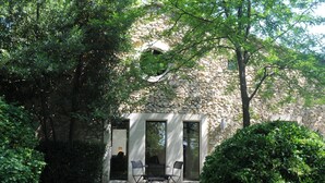 Ein Steinhaus mit einer kleinen Terrasse, auf der ein Tisch und Stühle stehen.