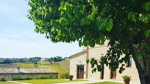 A building with a brick facade, a paved courtyard, and a view of the surrounding landscape.