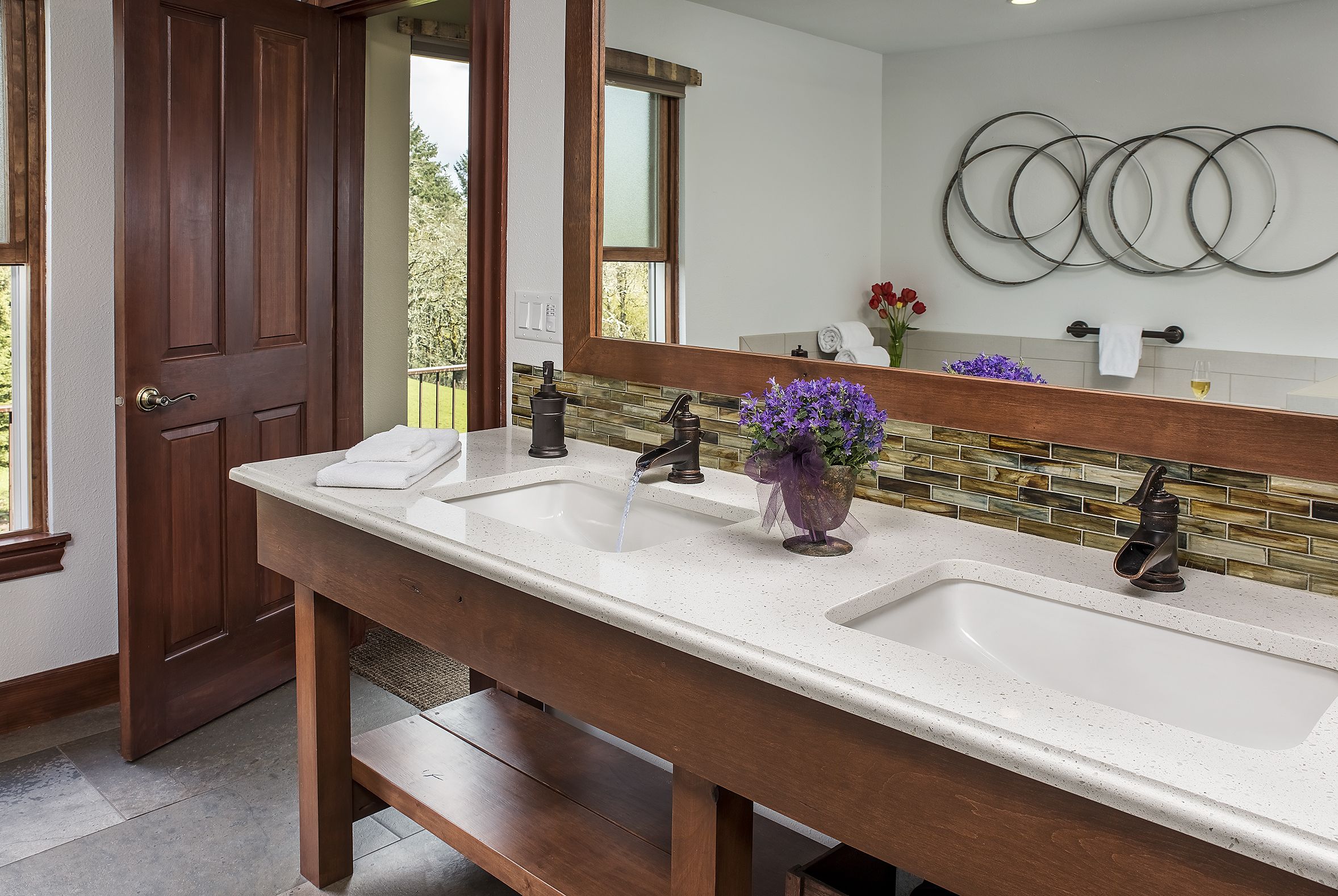 A bathroom with a double sink, wooden bench, and a large mirror.