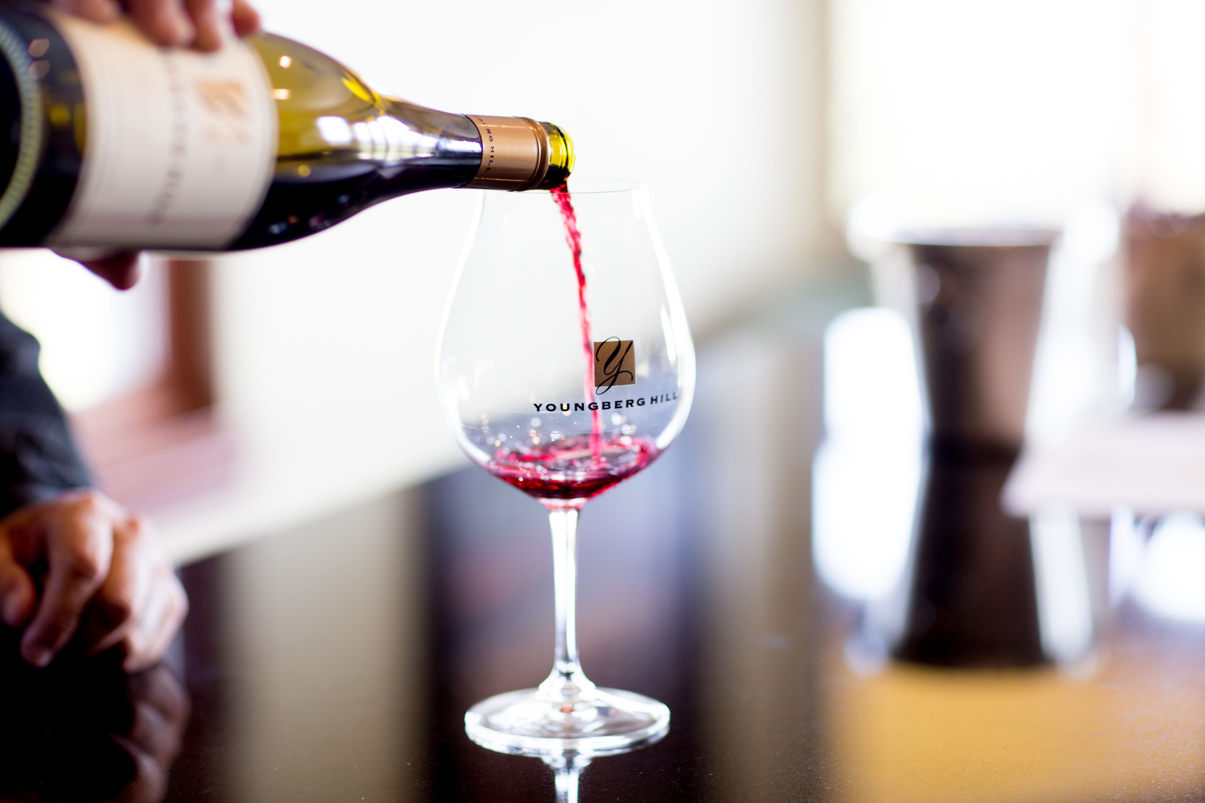 A wine bottle being poured into a glass labeled "Youngberg."