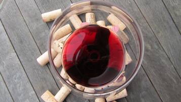 Una copa de vino tinto rodeada de corchos sobre una superficie de madera.