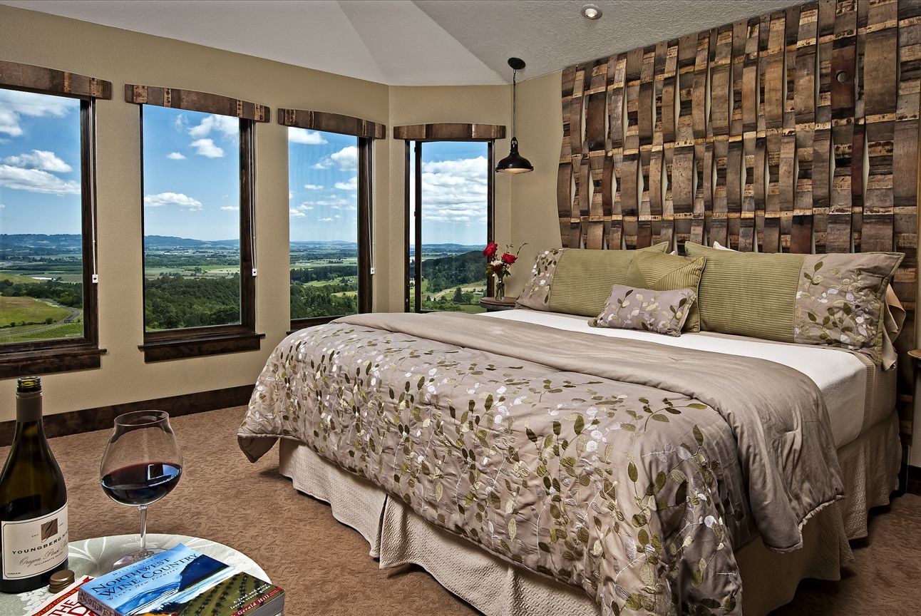 Un dormitorio con una cama grande, varias ventanas y vistas al campo.