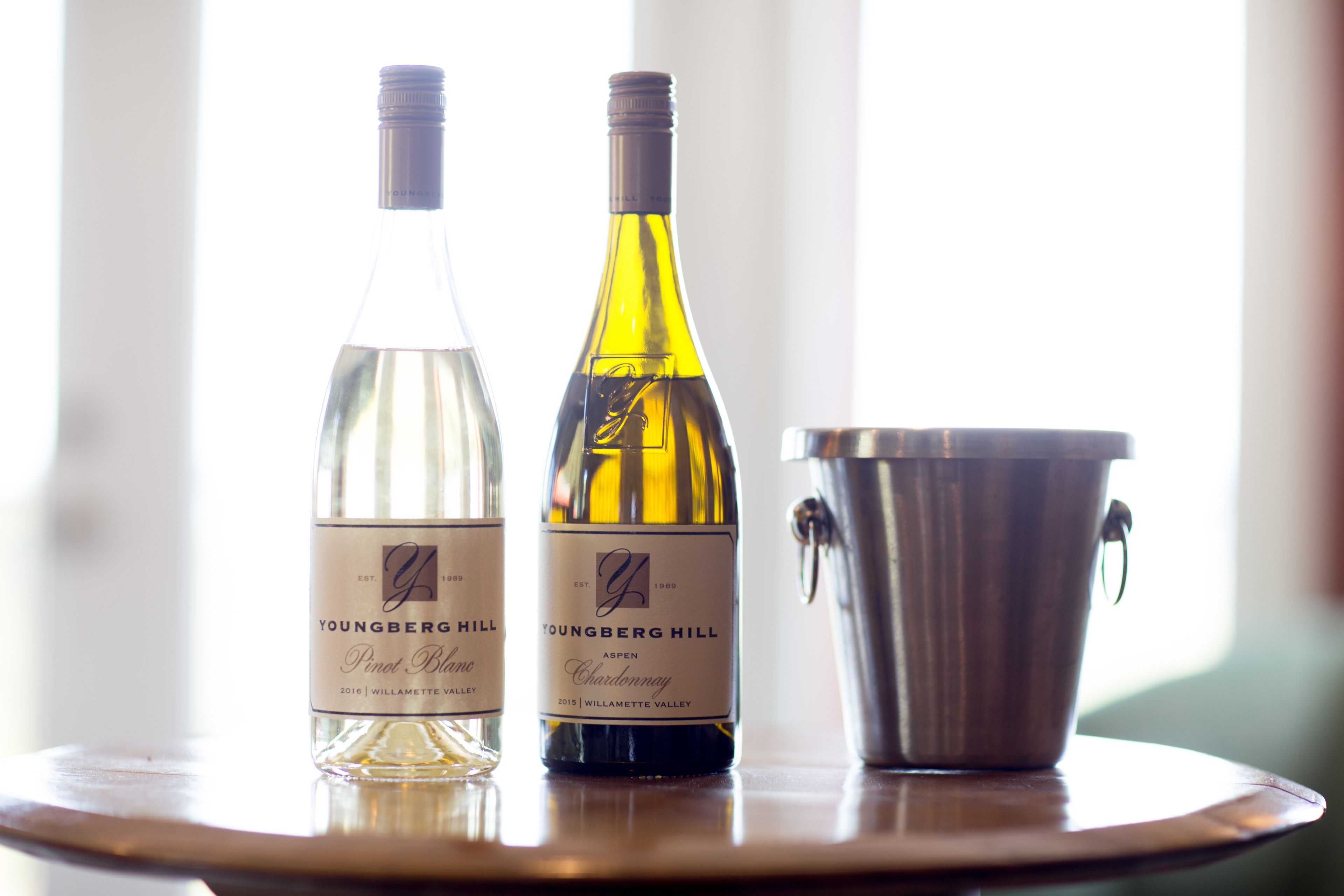 Two bottles of Youngberg Hill wine on a table with a metal bucket.