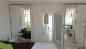 Ein Hotelzimmer mit Bett, Schreibtisch und Spiegel. Eine Tür führt in einen weiteren Raum.