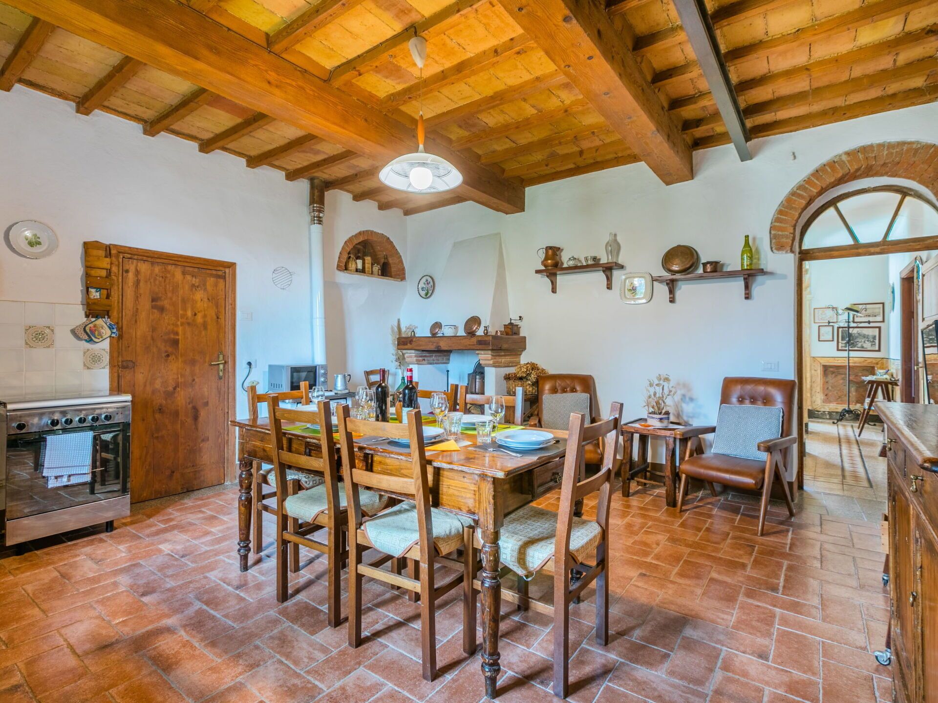 A rustic kitchen with wooden furniture, a tiled floor, and a brick oven.