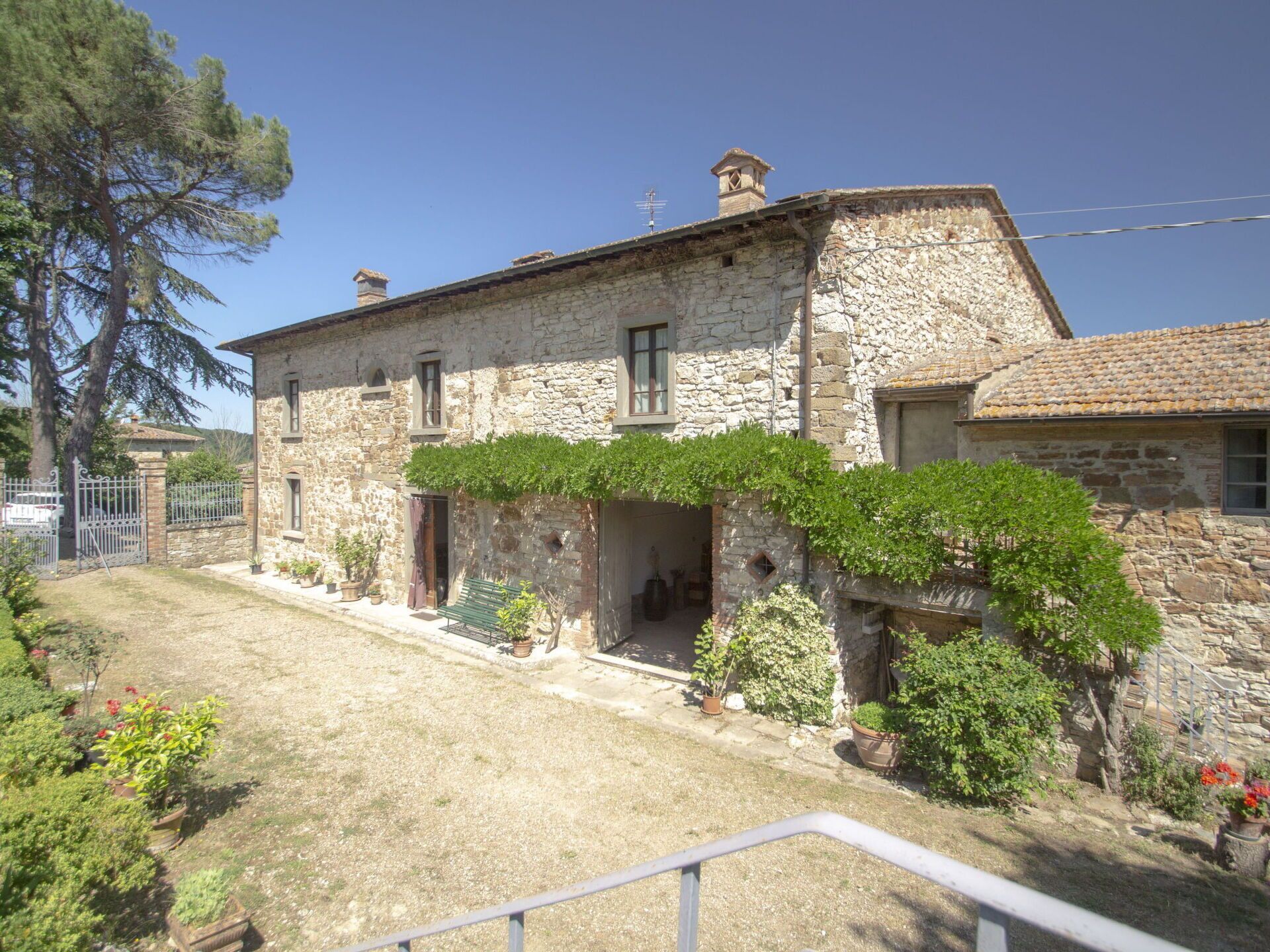 A stone building with a garden and a metal fence.