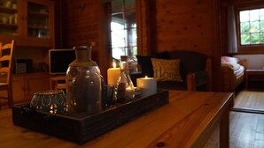 Un interior de madera con una mesa que sostiene una vela, un tarro de vidrio y un objeto decorativo.