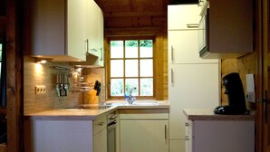 Una cocina compacta con armarios blancos, lavavajillas y cafetera.