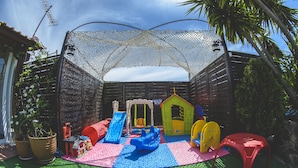 Ein Kinderspielbereich mit Rutsche, Schaukeln und einem kleinen Spielhaus.