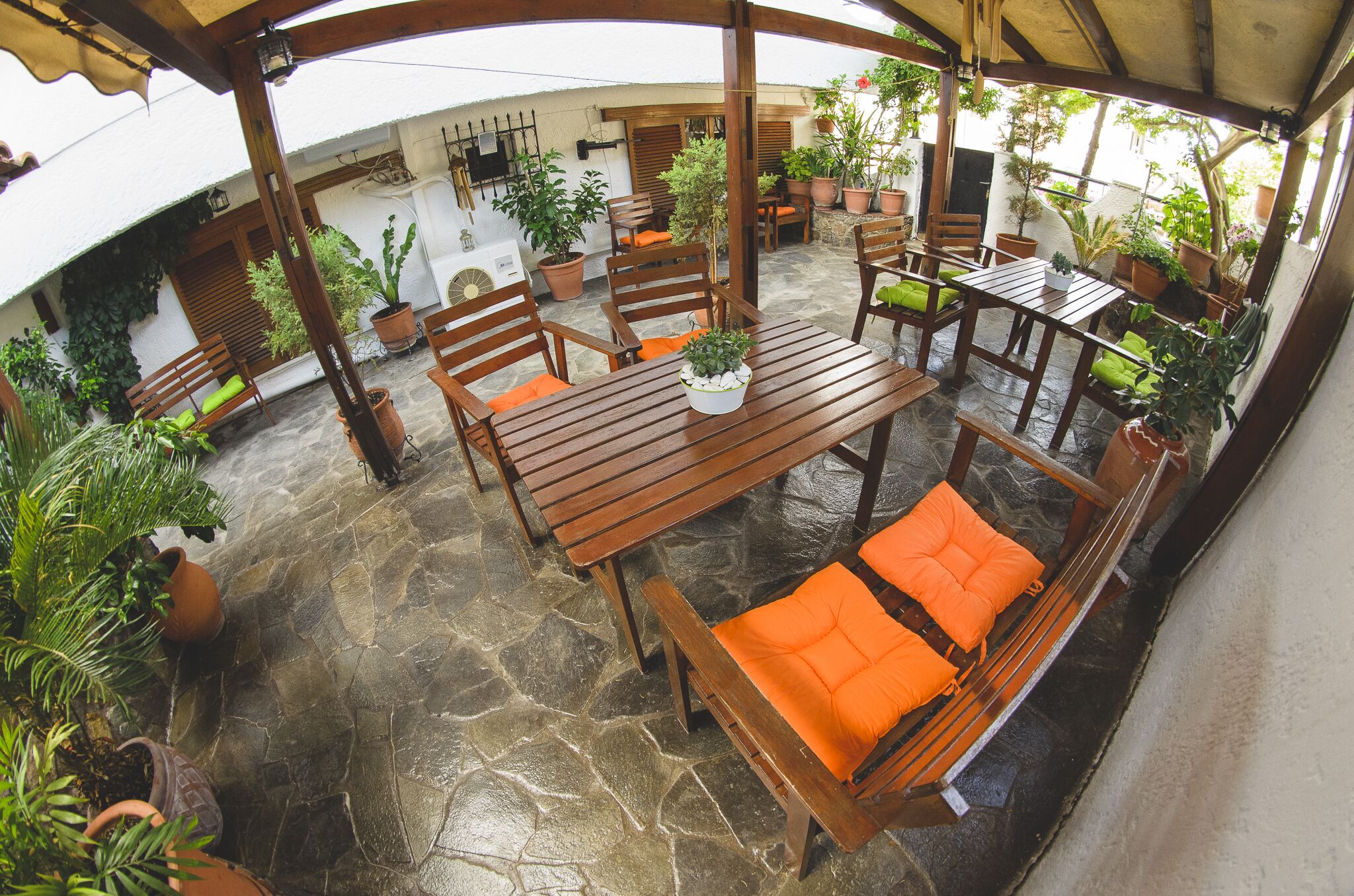 A covered patio with wooden furniture and potted plants.