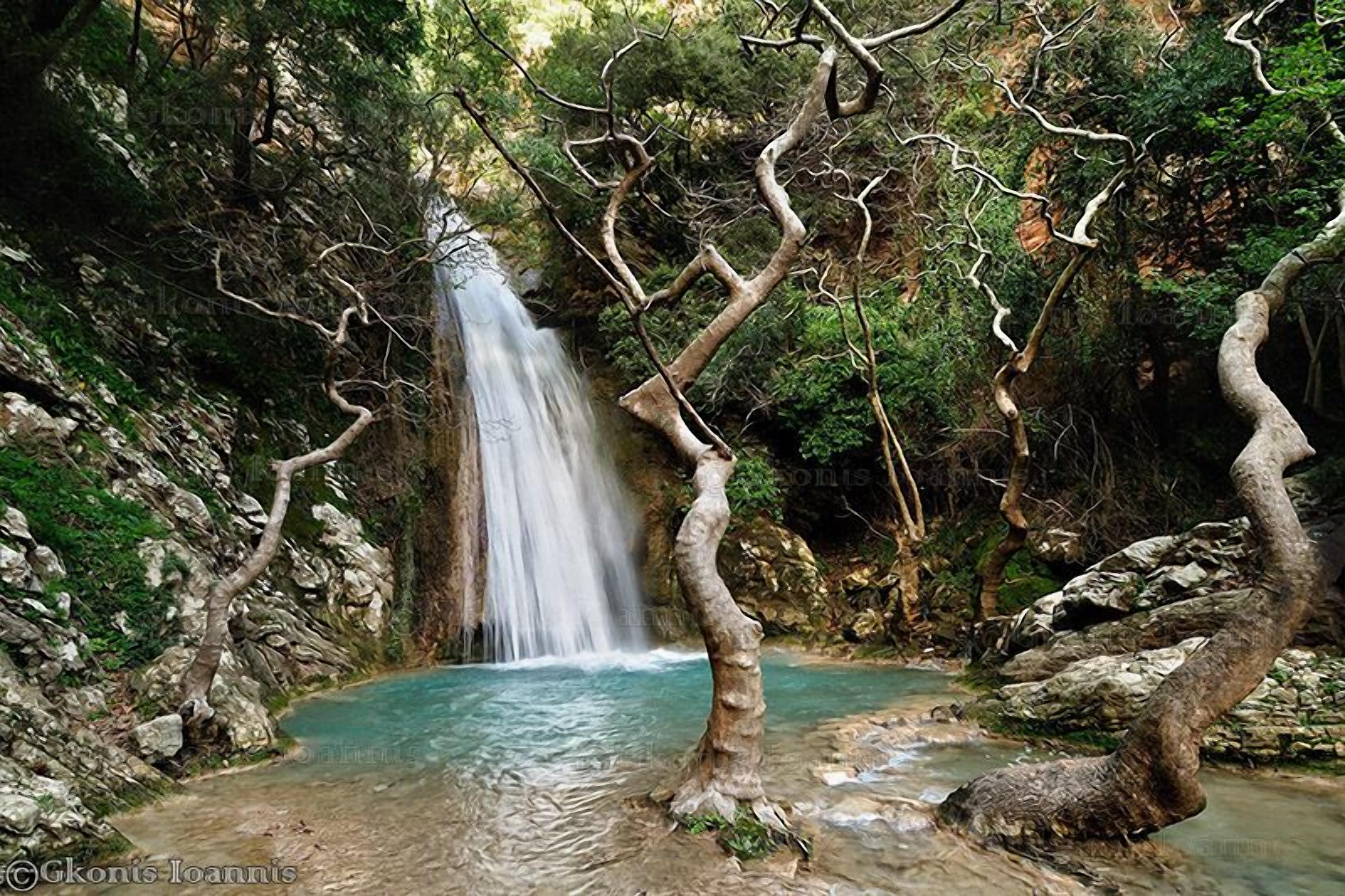 A waterfall surrounded by rocky terrain and trees.