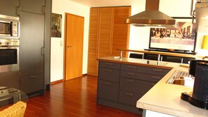 Une cuisine moderne avec des meubles gris, un plancher en bois et un four encastré.