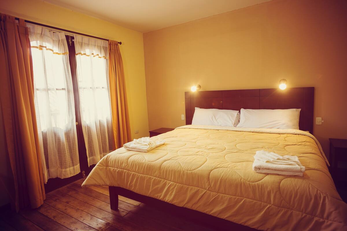 Ein Hotelzimmer mit einem großen Bett, Holzboden und Vorhängen.