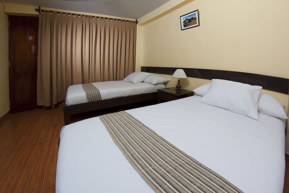 Ein Hotelzimmer mit zwei Einzelbetten, Holzboden, beiger Wand und einem gerahmten Bild.