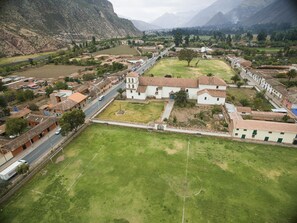 Surrounded by rolling hills and a mountainous backdrop, this village features a historic church with a bell tower, nestled among terraced fields and charming homes.