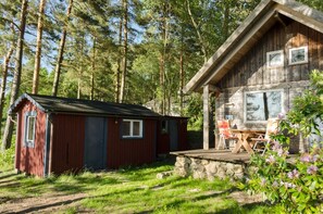 A rustic cabin with a wooden deck and a small shed.