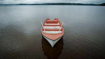 Un petit bateau orange à l’intérieur blanc, flottant sur une eau calme.