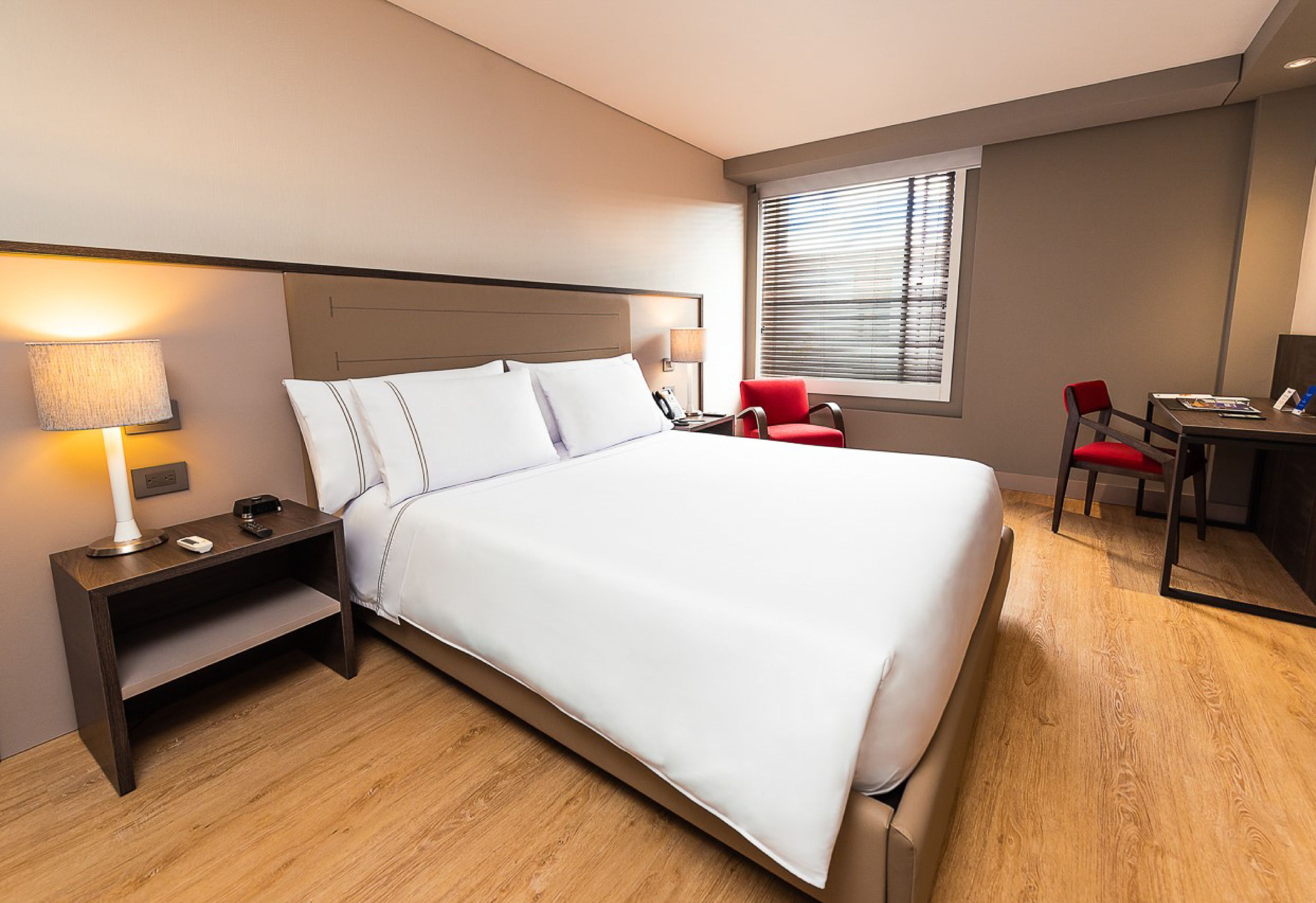 Ein Hotelzimmer mit einem großen Bett, Nachttischen, einem Schreibtisch und einem Stuhl.