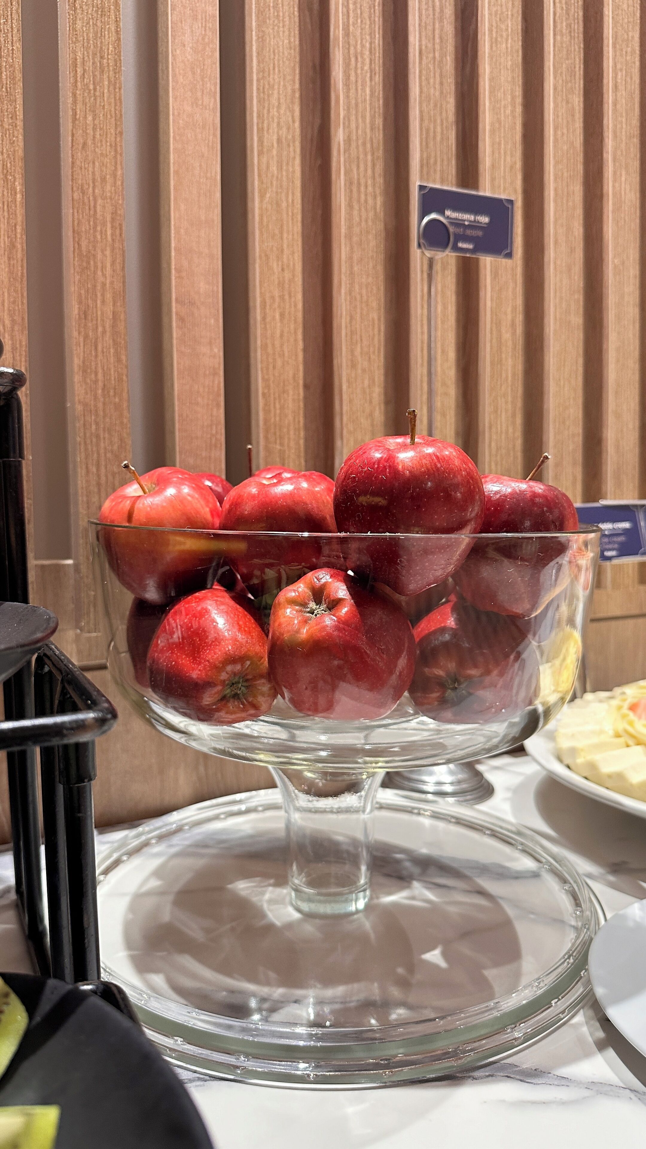 Un saladier en verre rempli de pommes rouges, posé sur une table.