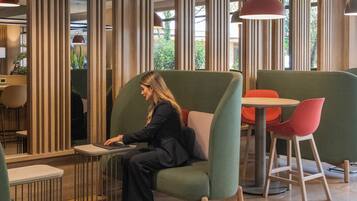 A modern interior with seating areas, a person using a laptop, and vertical wooden panels.