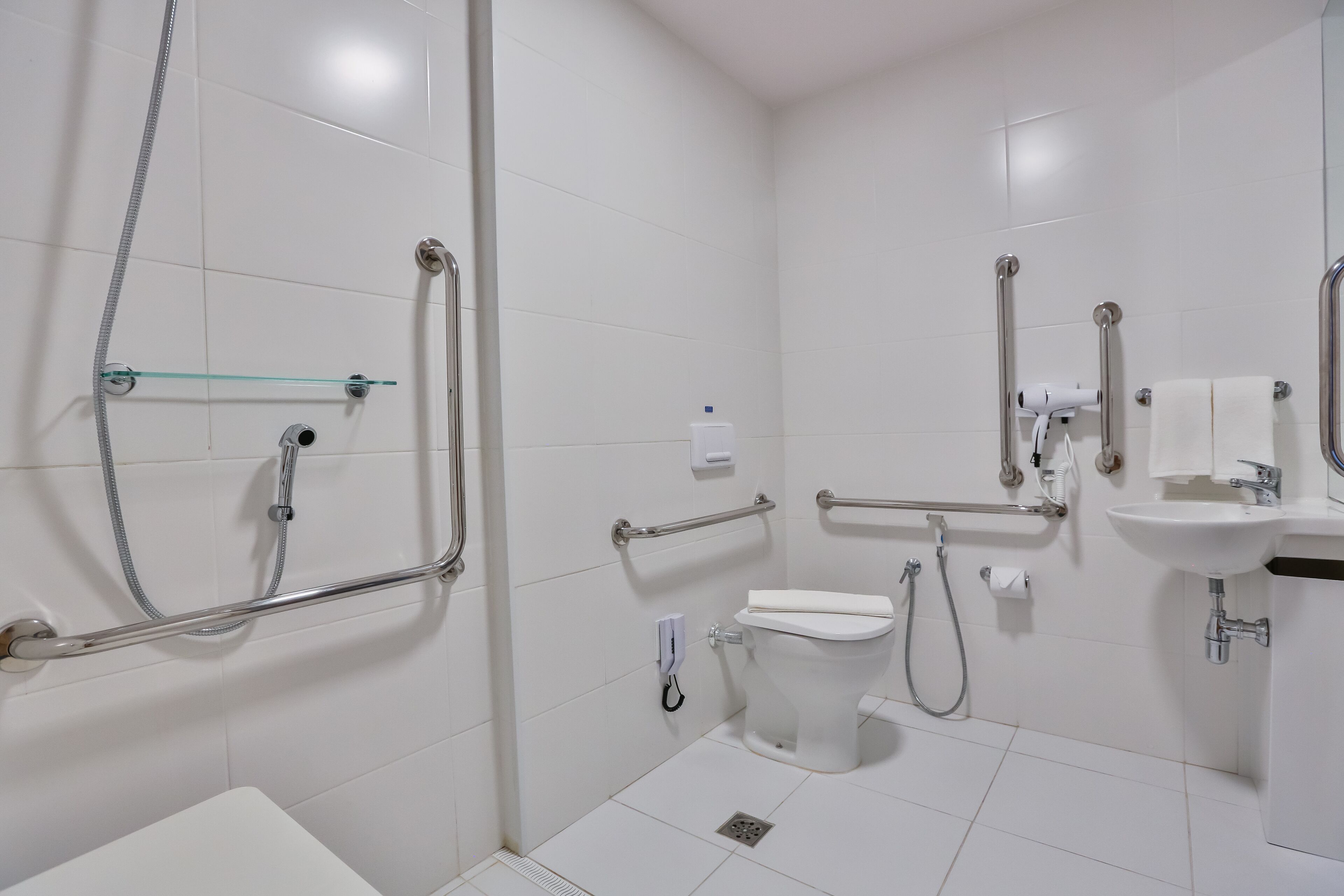Een moderne badkamer met witte tegels, een toilet, een wastafel en een douchehoek.