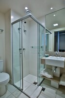 Un baño moderno con ducha de vidrio, inodoro blanco y lavabo con encimera.