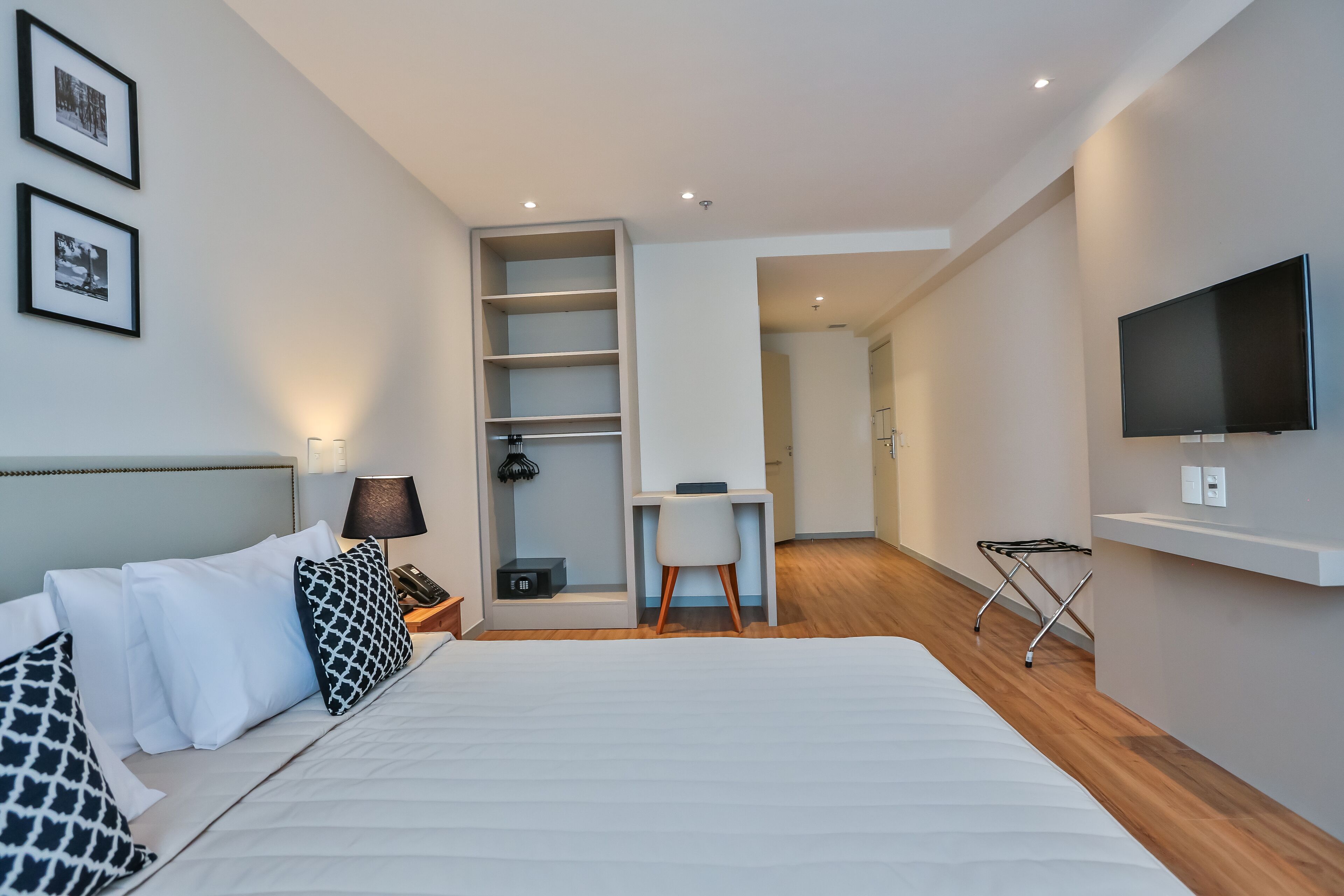 Una habitación de hotel moderna con una cama grande, un escritorio, un televisor y un vestidor.