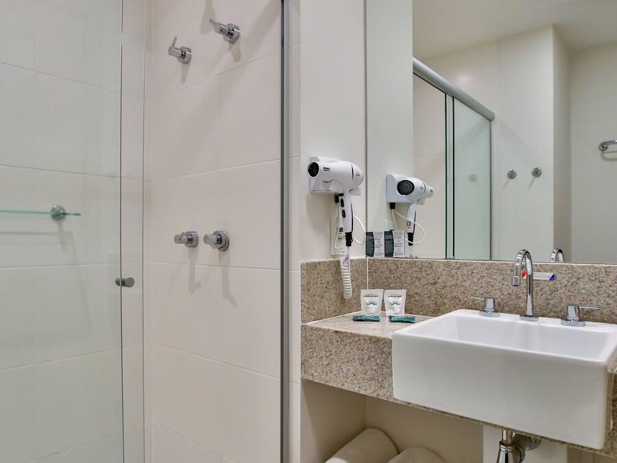 A modern bathroom with a glass shower enclosure, a sink with a mirror, and a towel rack.