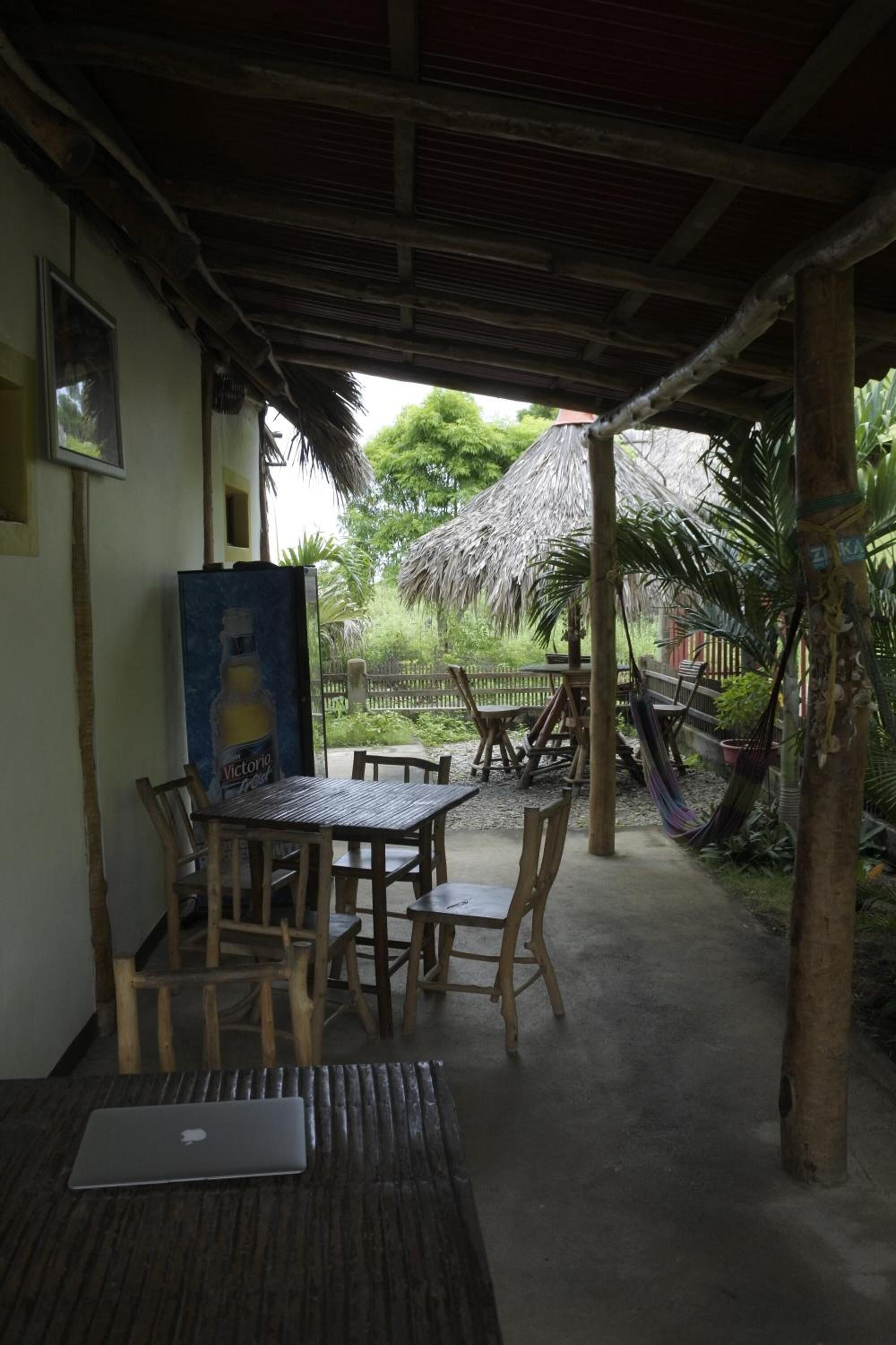 An outdoor seating area with a table and chairs, a hammock, and a thatched roof structure.
