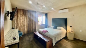 Quarto com cama, escrivaninha, banco e janela.