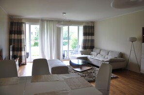 A modern living room with a sofa, ottoman, coffee table, and dining area with placemats.