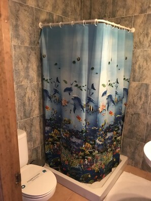 A bathroom with a shower curtain featuring an underwater scene, a toilet, and a bathtub.