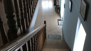 A staircase with wooden balusters leading to a landing area with a potted plant and a small table. - Posada La Maza (Arnuero)