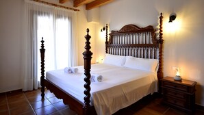 A bedroom with a four-poster bed, wooden headboard, bedside lamps, and a nightstand with a lamp. - 44059 Sa Torre nova - 44059 S'Illot - Sa Torre nova (San Lorenzo)