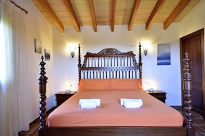 A four-poster bed with a wooden headboard, two bedside tables, and a nightstand.
