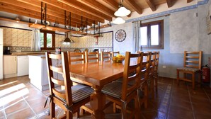 A spacious kitchen with wooden beams, a dining table surrounded by chairs, and a clock on the wall. - 44059 Sa Torre nova - 44059 S'Illot - Sa Torre nova (San Lorenzo)