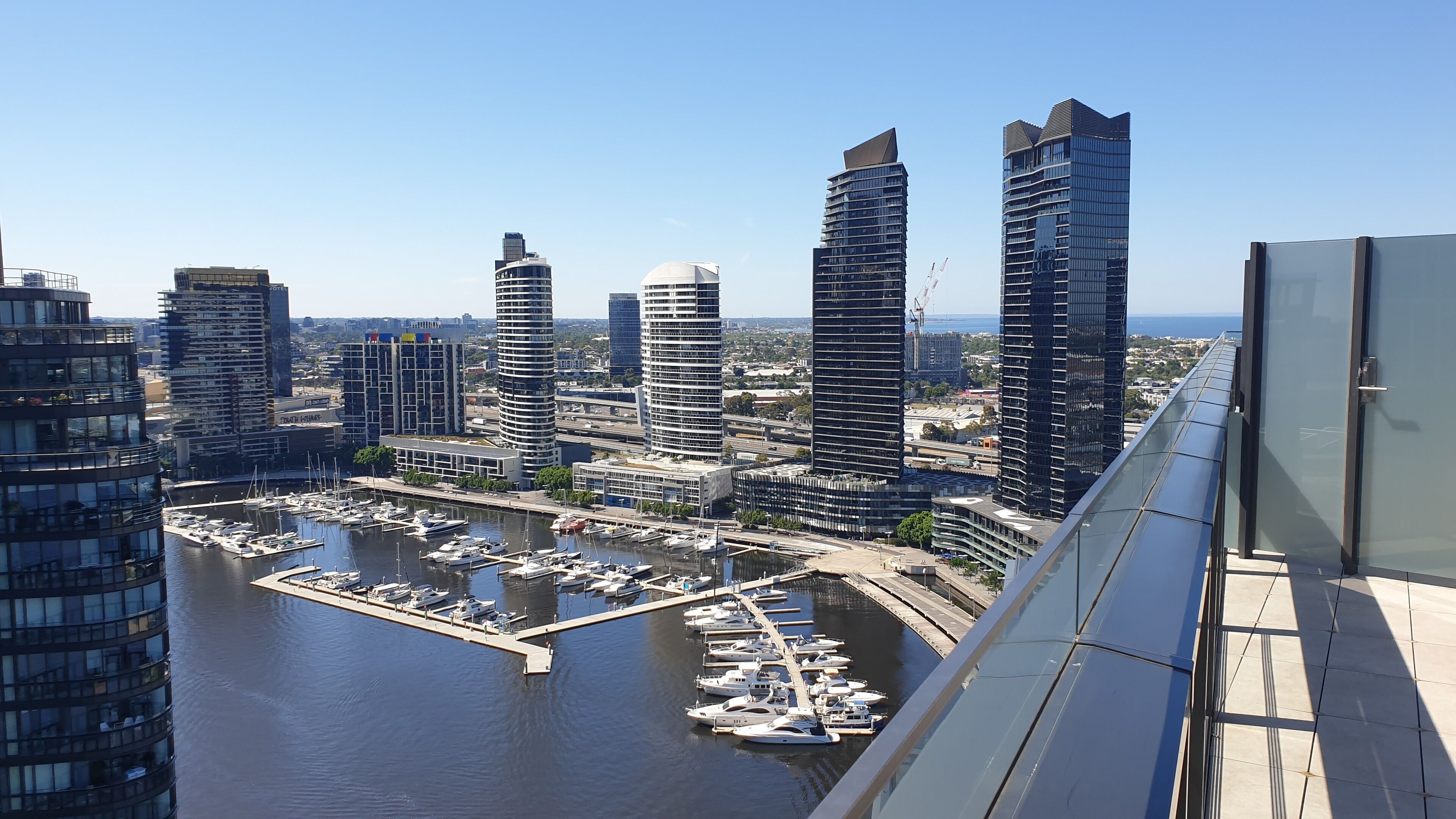 A marina with yachts docked, surrounded by modern high-rise buildings.