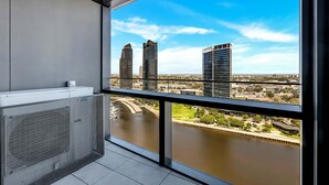 A balcony with a view of a river and cityscape, including modern buildings and a bridge.