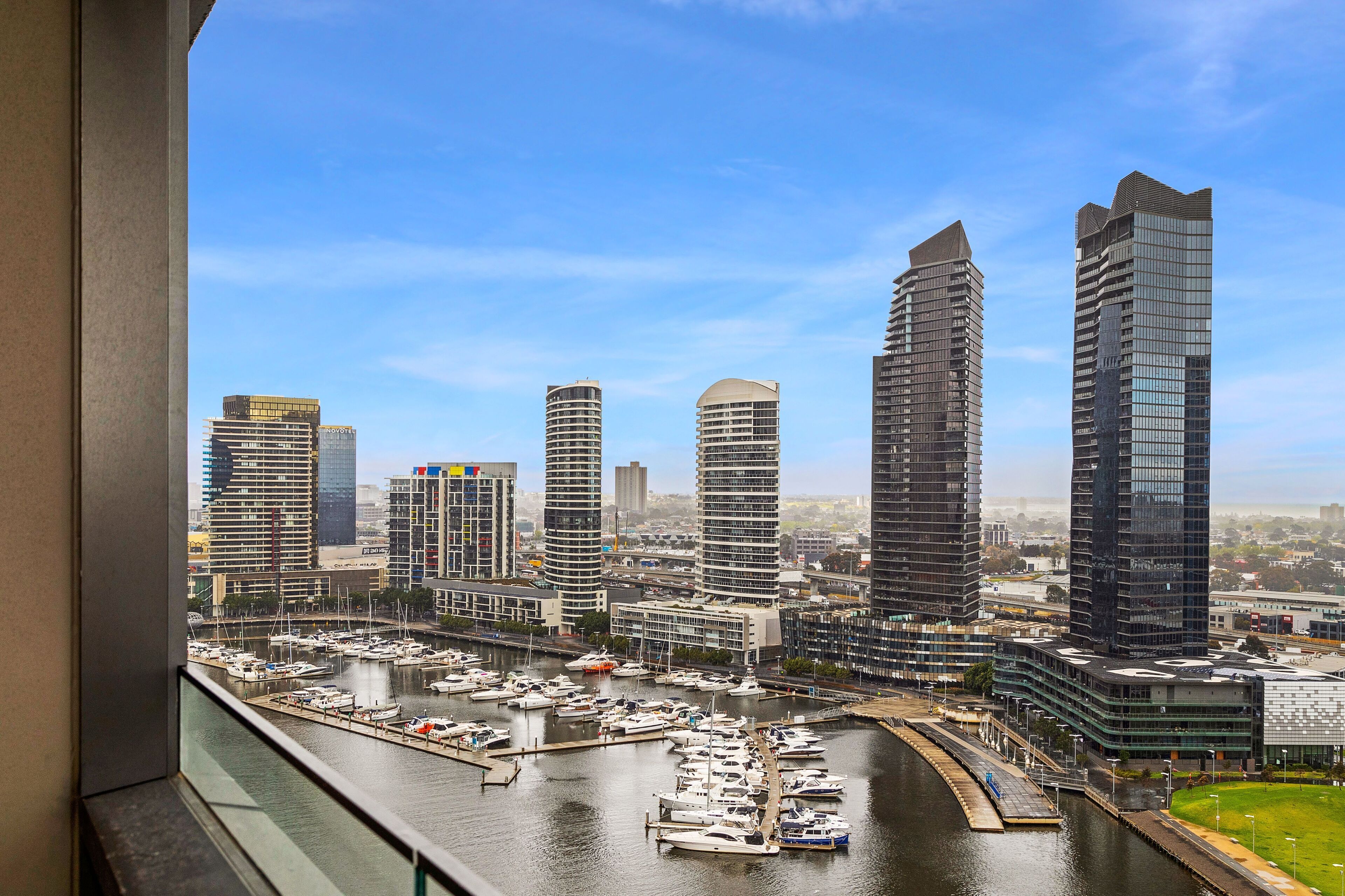 A marina with boats docked, surrounded by modern high-rise buildings.