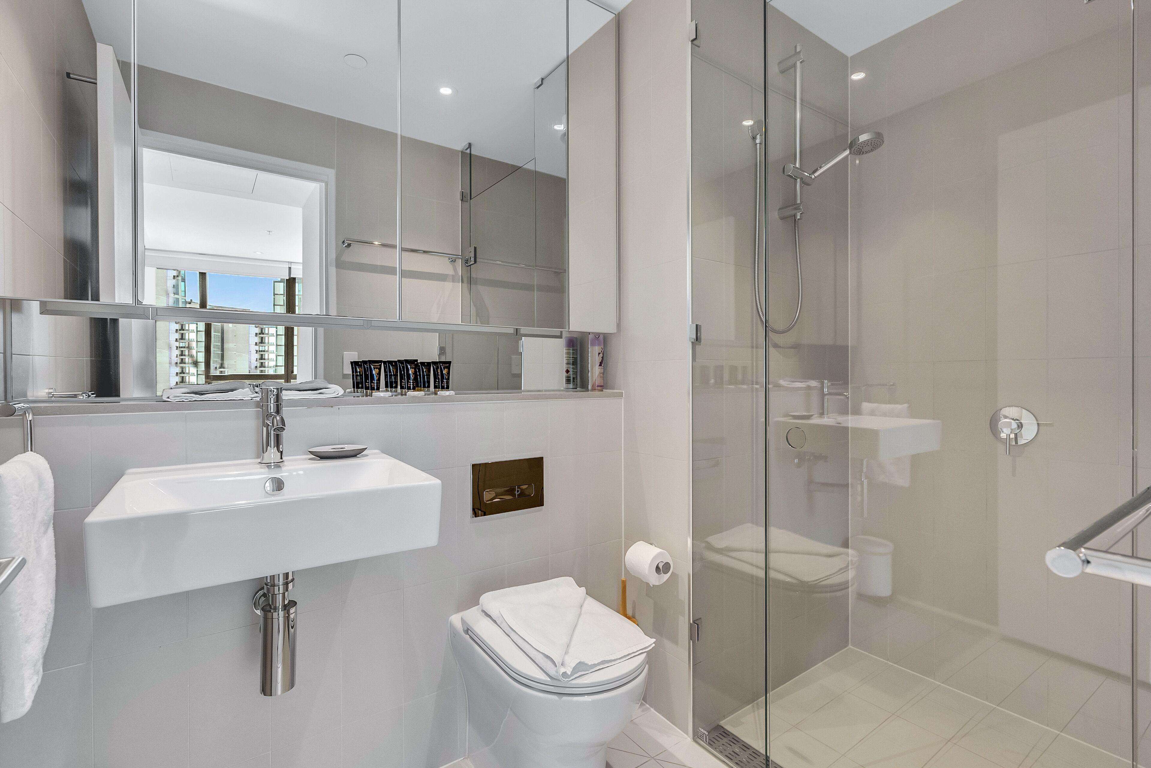 Un baño moderno con ducha de vidrio, un lavamanos blanco y un inodoro.