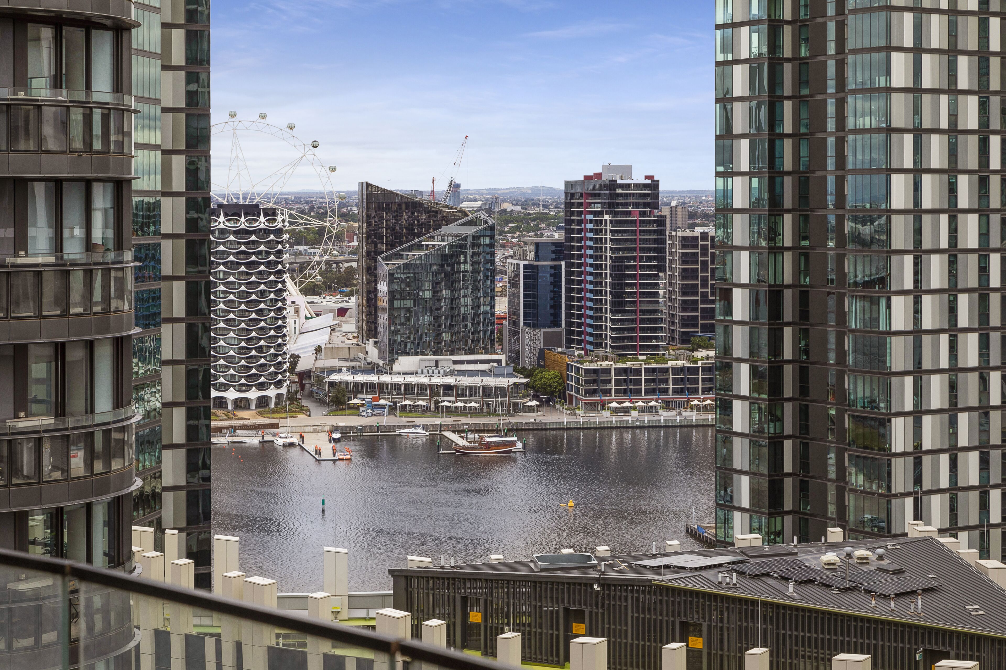Ein Hochhaus mit moderner Architektur, Blick auf das Wasser und einem Riesenrad im Hintergrund.