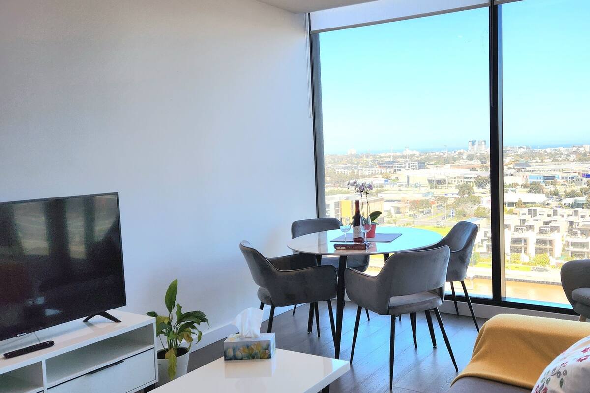 Un salon moderne avec une grande télévision, une table à manger et un canapé.