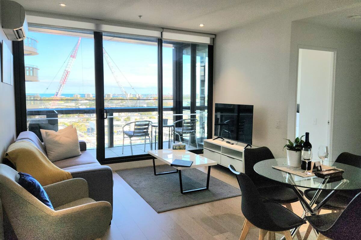 Un salon moderne comprenant un canapé, une table basse et un coin repas avec des chaises et un téléviseur.