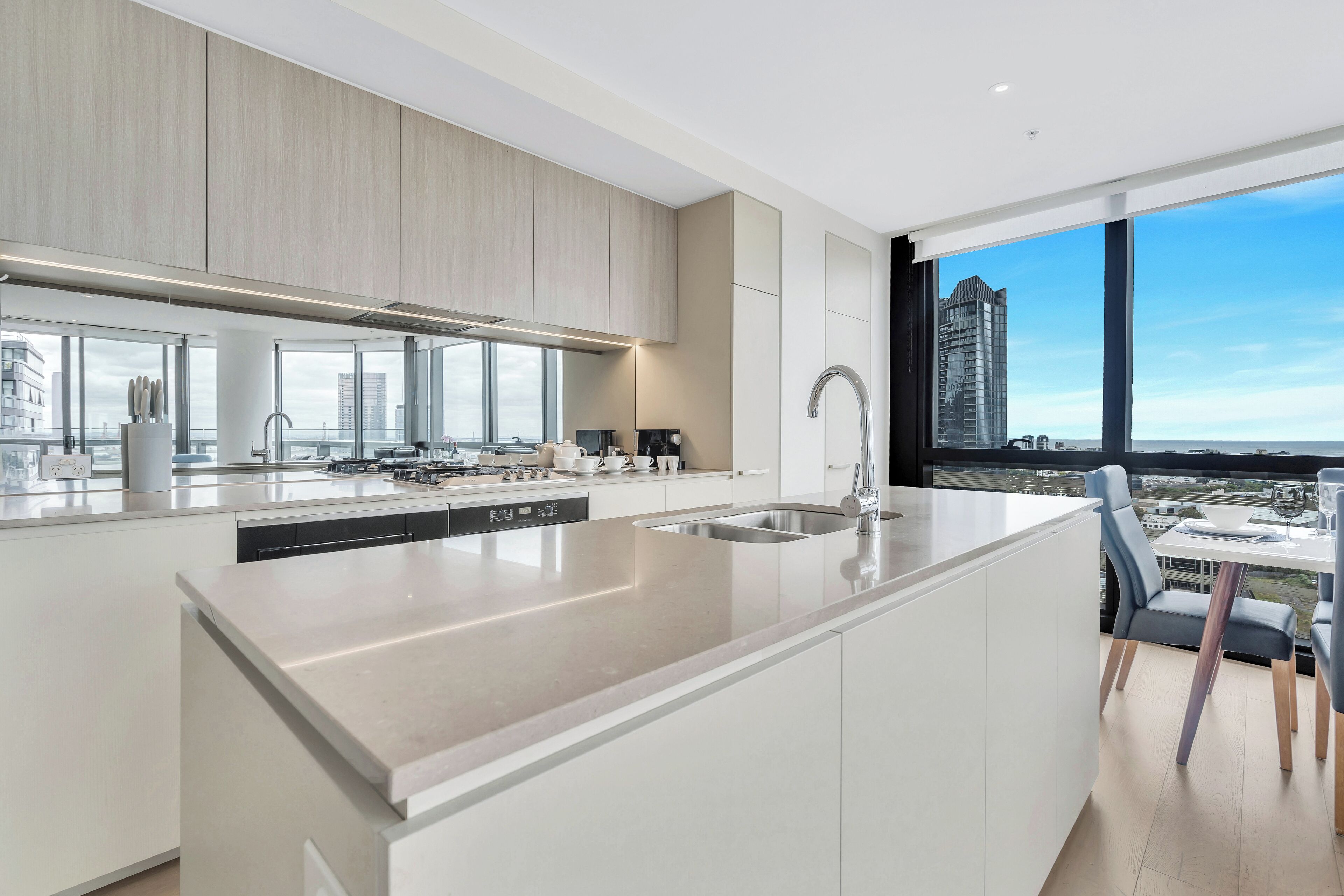 A modern kitchen with a large island, built-in appliances, and a view of the city through large windows.