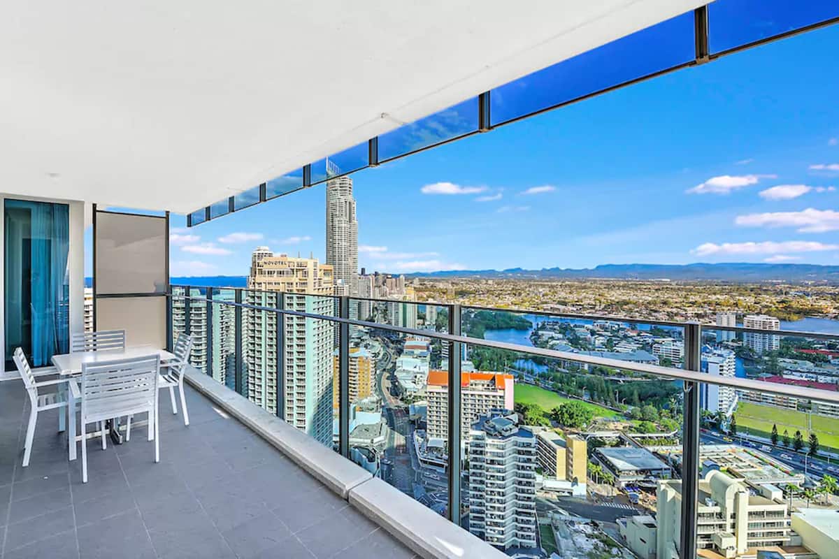 Een balkon met uitzicht op de stad, inclusief een hoog gebouw en een rivier.