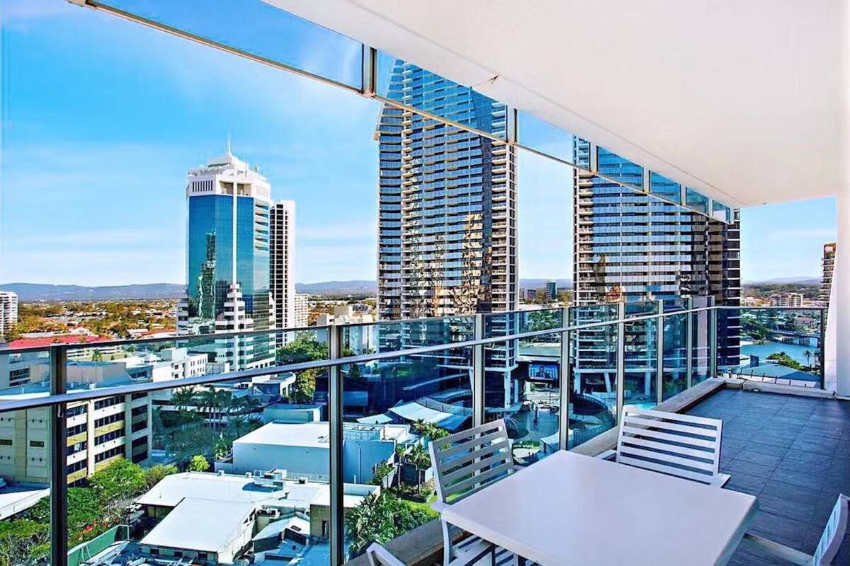 Een moderne hotelkamer met een ruim balkon, met een panoramisch uitzicht op de stad en omliggende gebouwen.
