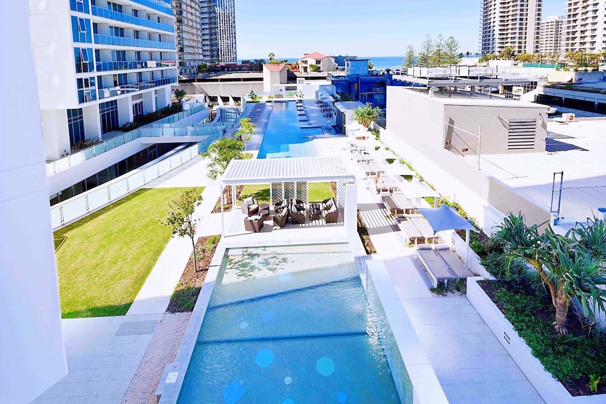 Een modern hotel met een zwembad op het dak, terrasplaatsen en uitzicht op de skyline van de stad.