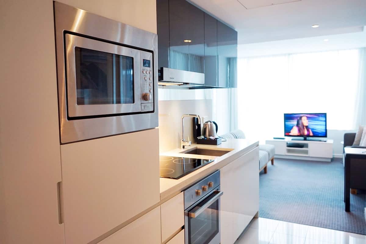 Een moderne keuken met een ingebouwde magnetron, oven en spoelbak. In de woonkamer staat een televisie met uitzicht op het buitengebied.